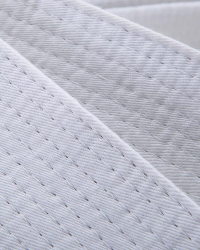 Nahaufnahme des Stoffes und der Nähte eines weißen Kampfsportgürtels.