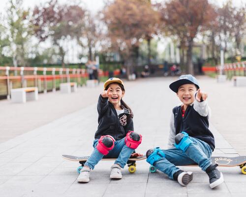 Kids sitting on a skateboard laughing