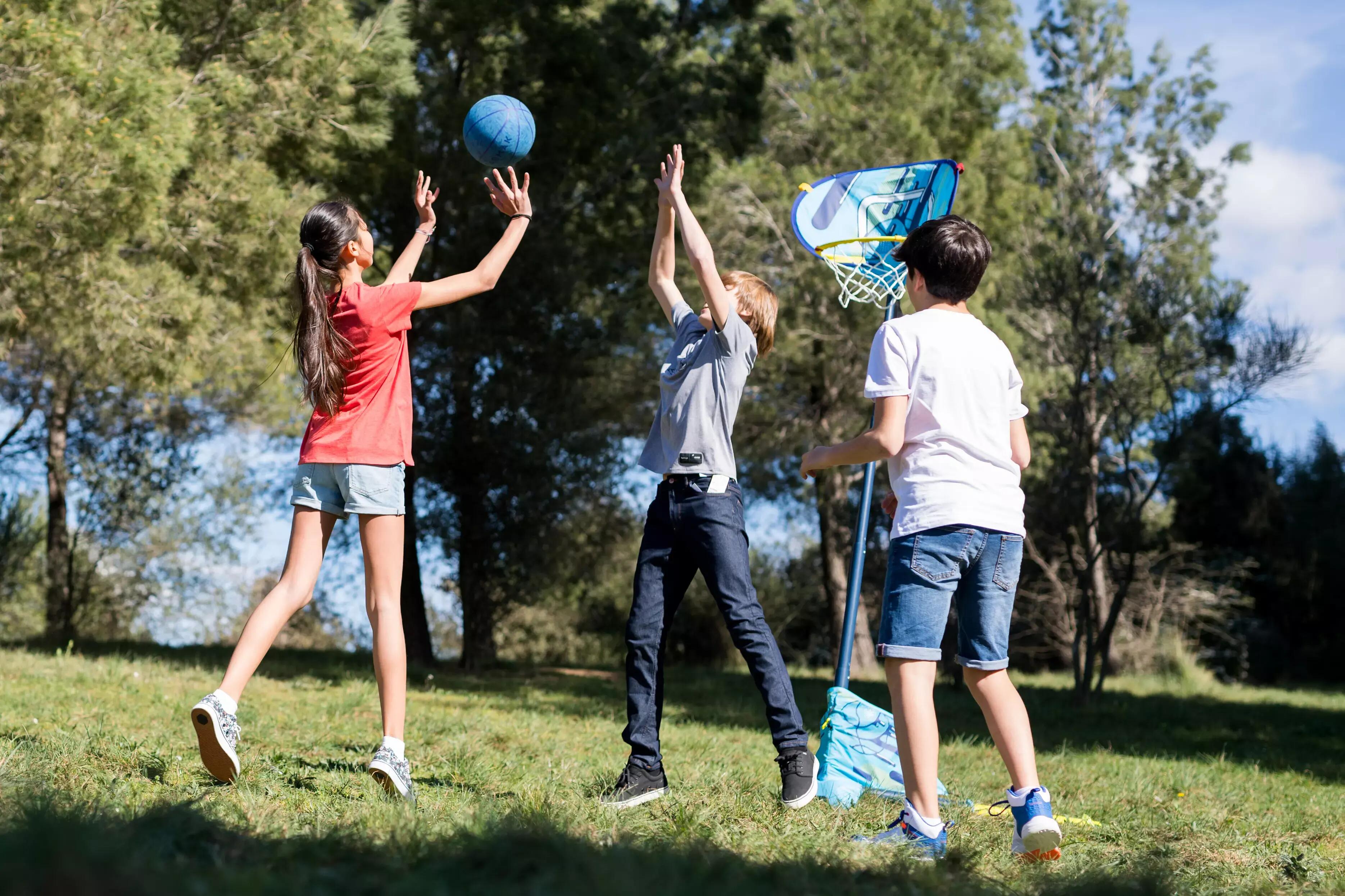 Boy and man playing with portable basketball hoop in a courtyard