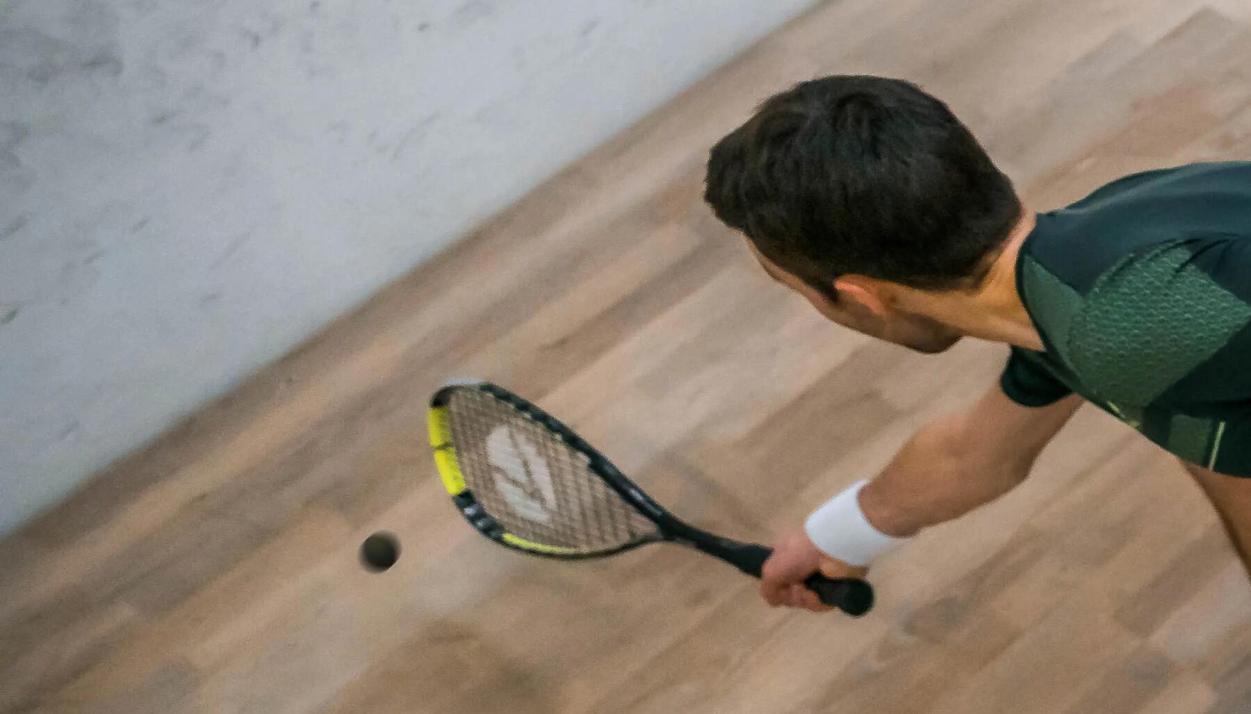 Man hitting a squash ball with his racket