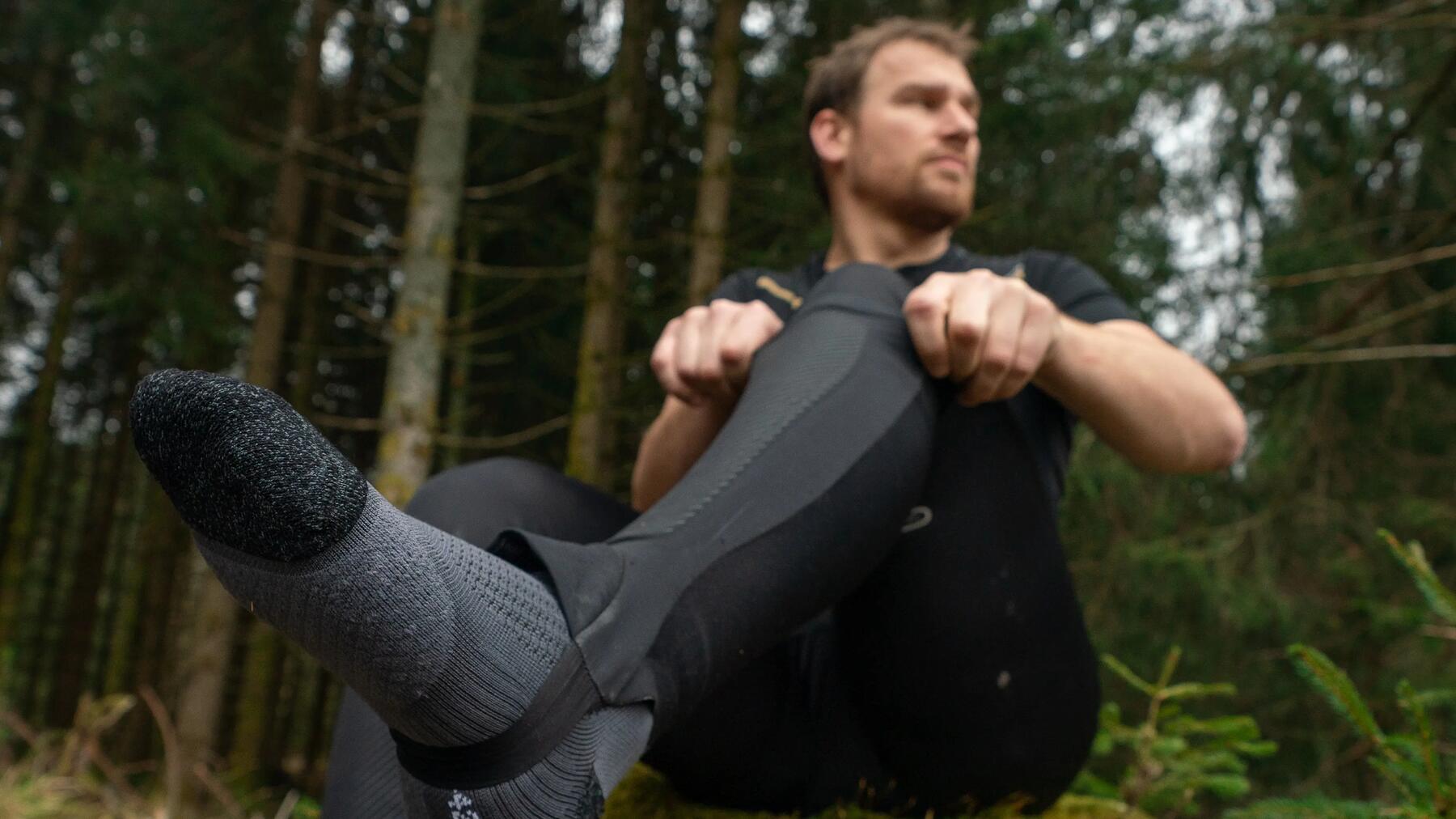 Ein Mann sitzt im Wald und dehnt sich dynamisch