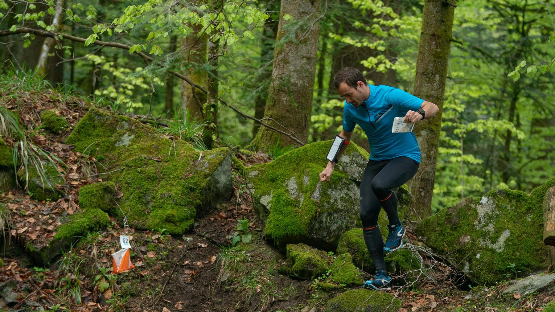 Geocaching Lösung finden, Mann läuft durch den Wald mit Karte