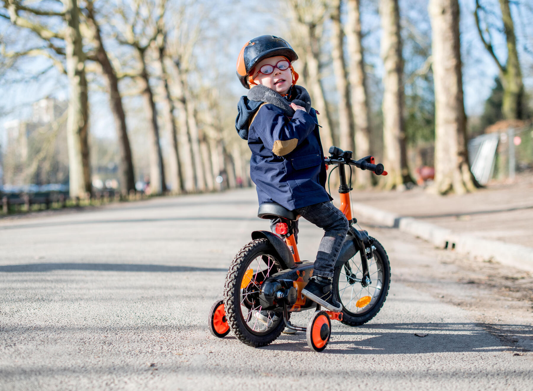 Ett barn sitter på en cykel med stödhjul