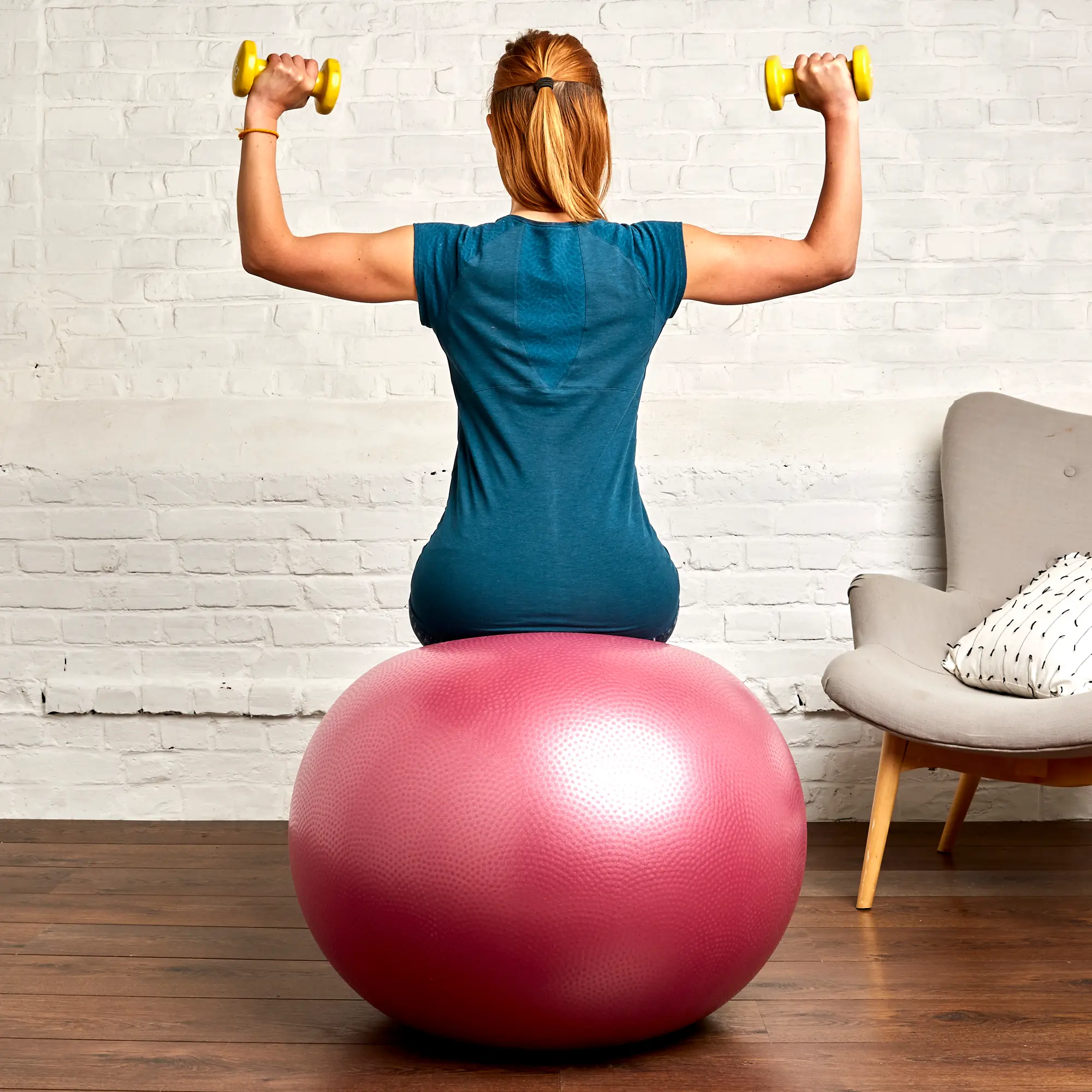 mulher de costas sentada numa bola de pilates