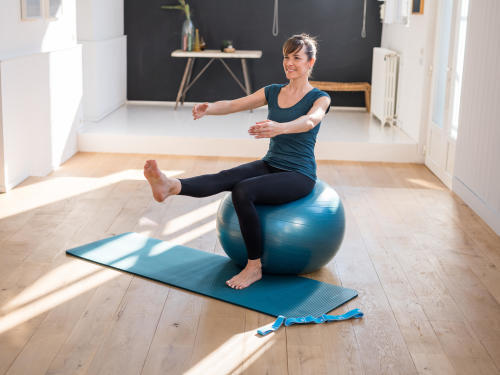 mulher a praticar exercício com uma bola de pilates, um tapete e um elástico