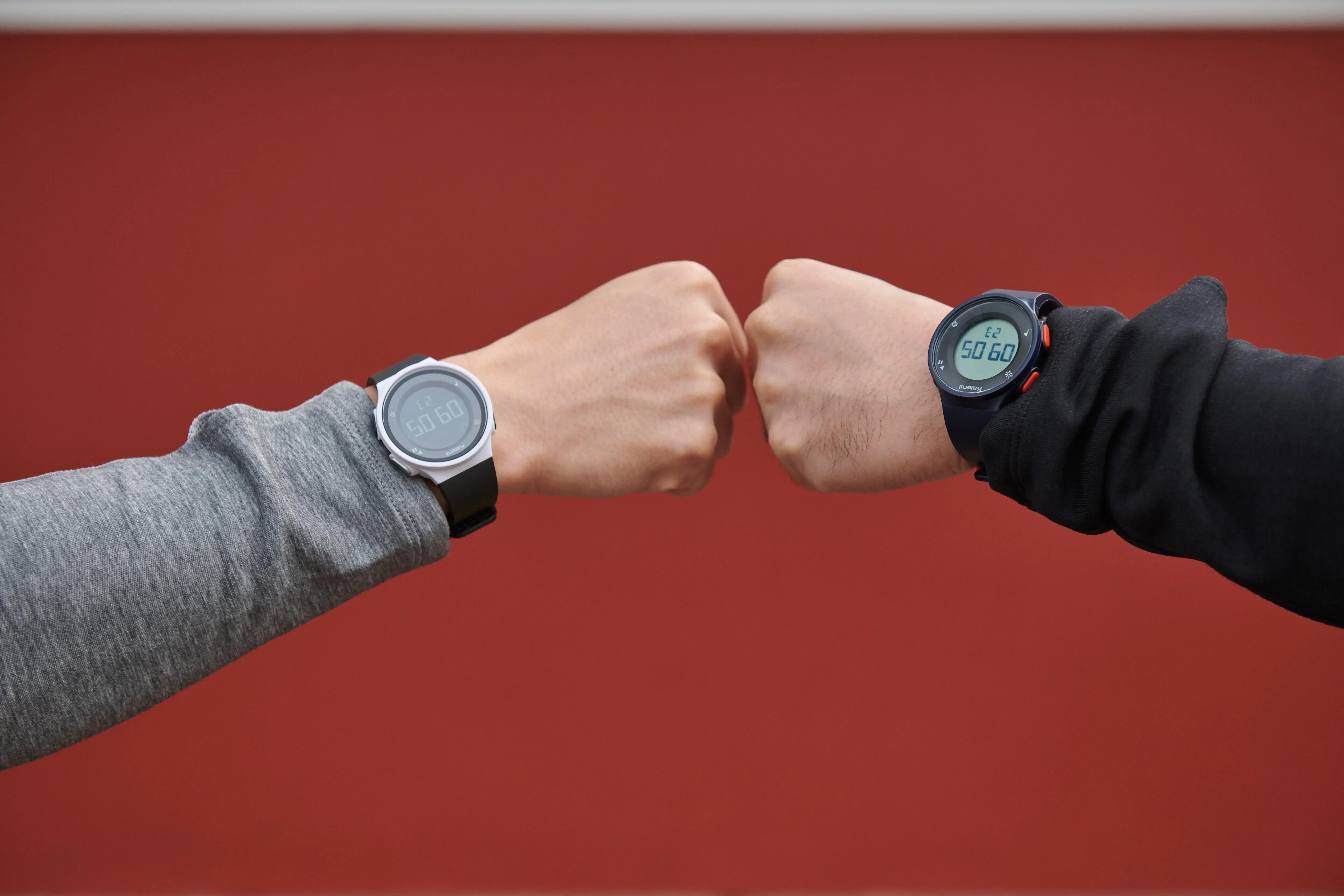 Two people wearing digital watches during a fist bump