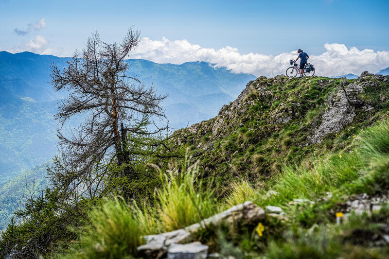 mężczyzna w kasku stojący przy rowerze w górach 