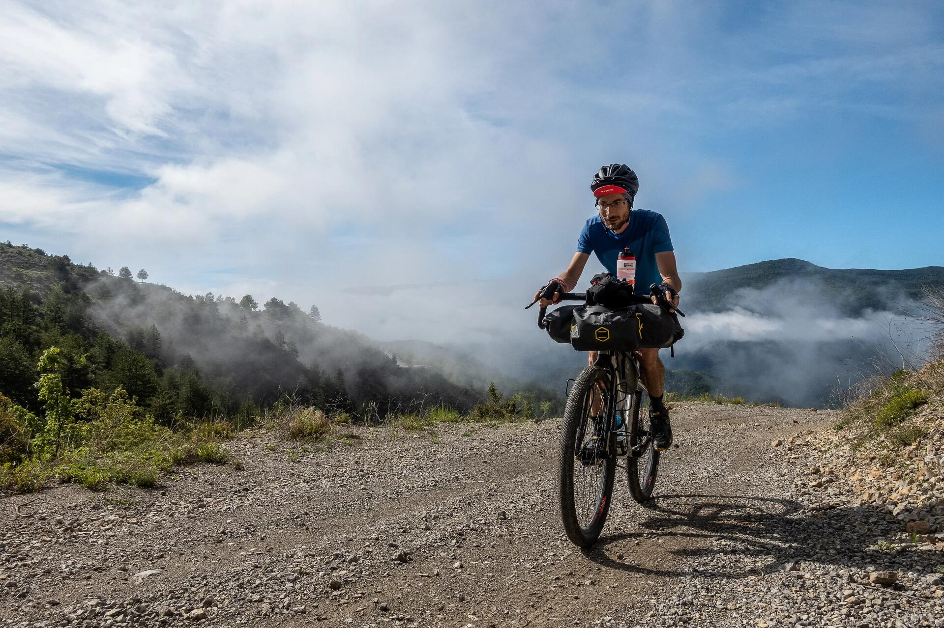 Mężczyzna w kasku jadący rowerem trekkingowym w terenie