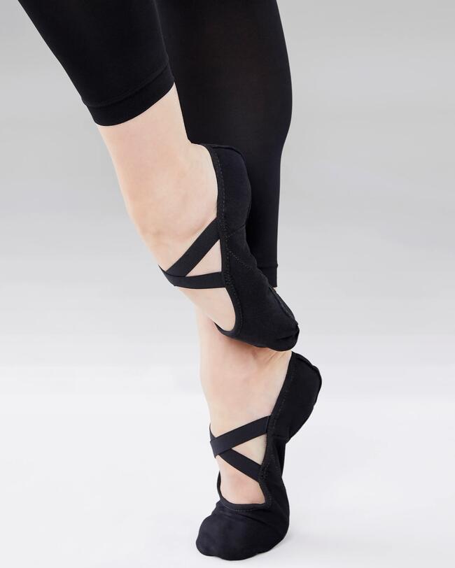 Eine Person trägt schwarze Ballettschuhe.