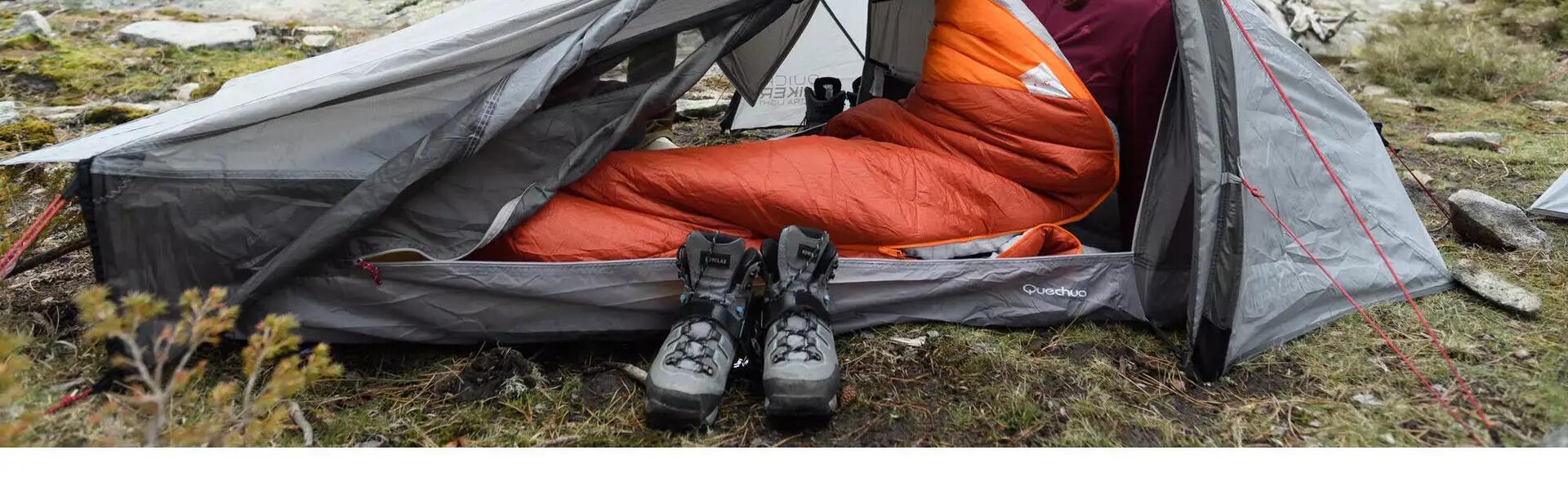A woman in a sleeping bag inside her trekking tent