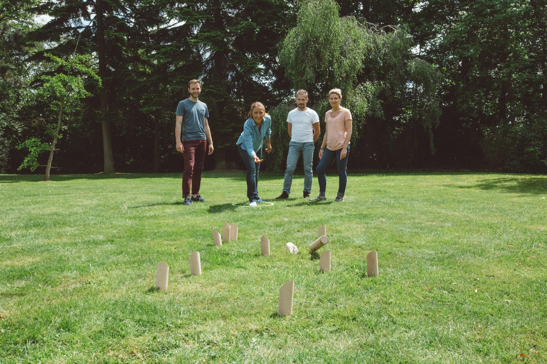 een groep mensen speelt een partij fins kegelspel en iemand gooit 1 kegel omver