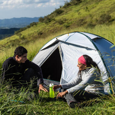 Zwei Personen sitzen vor einem Trekkingzelt im Gras