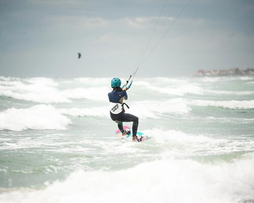 Rückenansicht einer Frau beim Kitesurfen auf dem offenen Meer