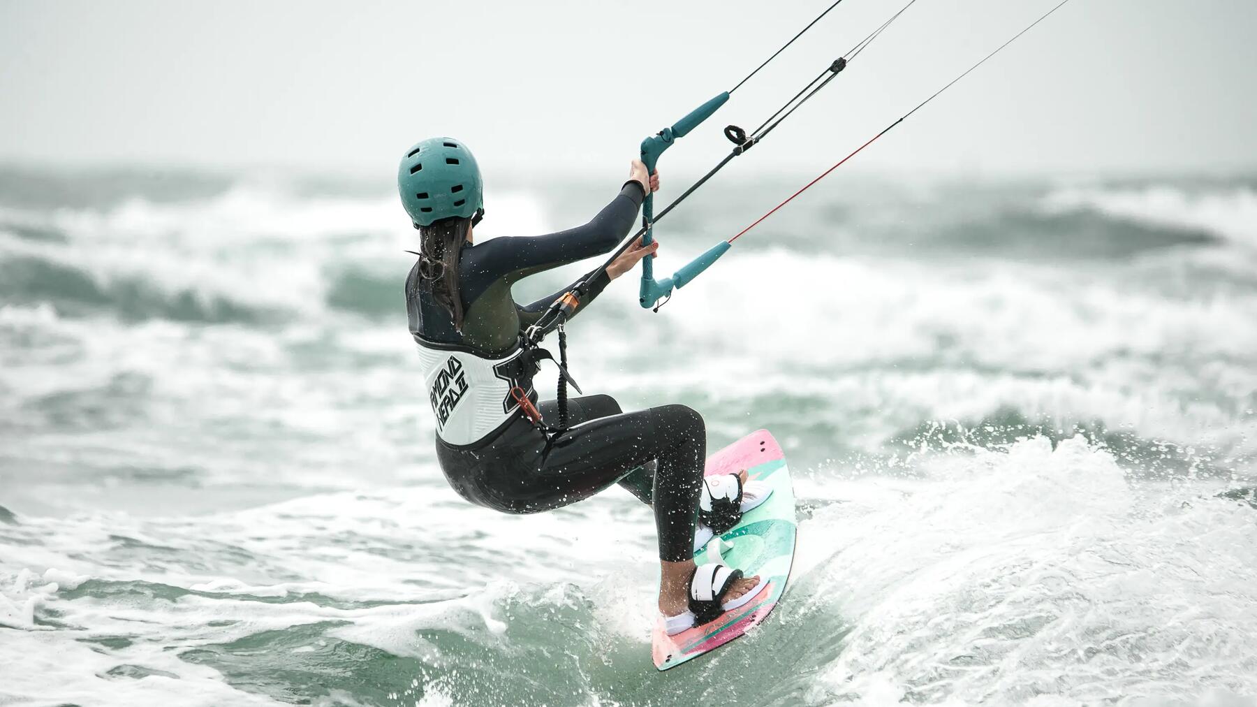 Eine Kitesurferin von hinten gesehen, wie sie über die Wellen gleitet
