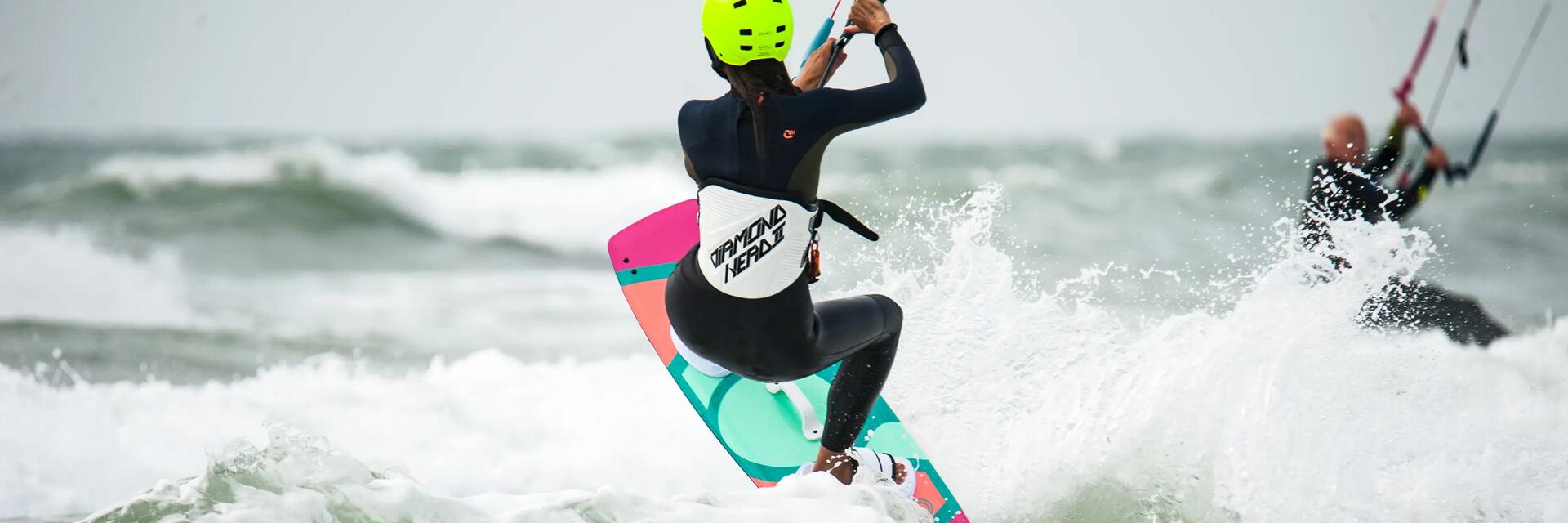 Kobieta w kasku ucząca pływać się na kitesurfingu