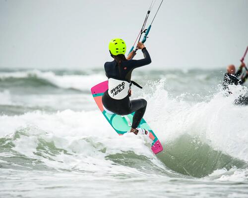 Kobieta w kasku ucząca pływać się na kitesurfingu