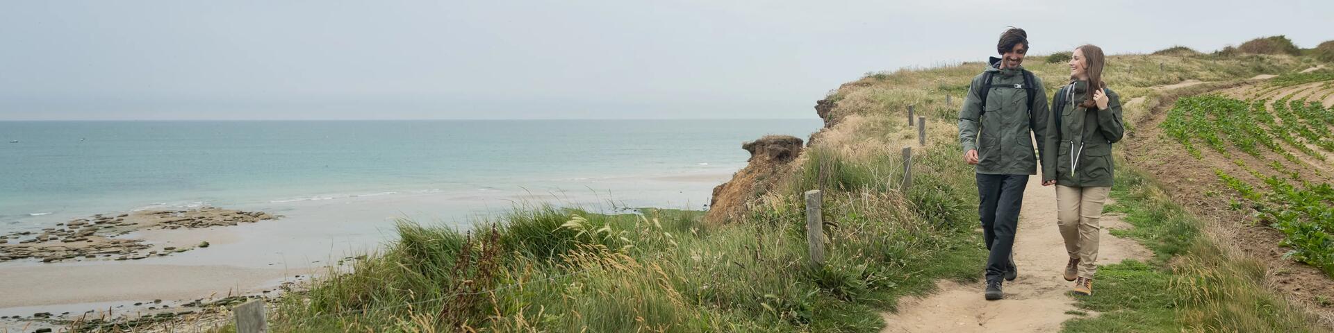 A couple walking on a coastal path in waterproof hiking jackets