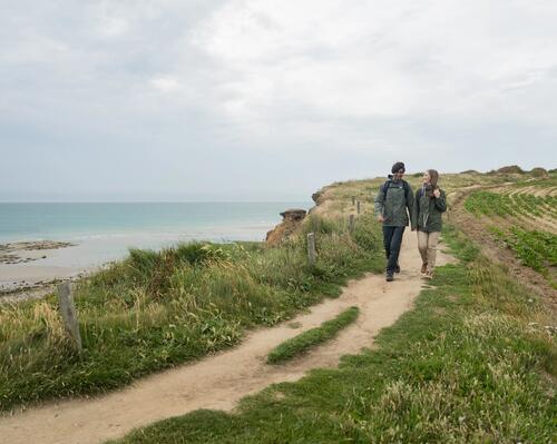 Una pareja caminando por un sendero costero con chaquetas impermeables para caminatas
