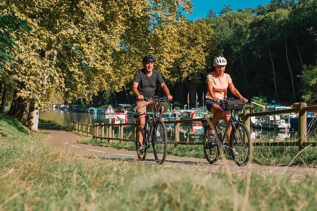 Kobieta i mężczyzna w kaskach jadący rowerami hybrydowymi