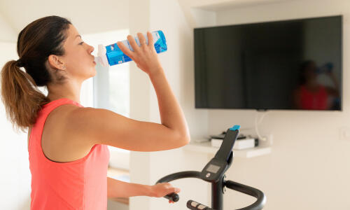 Une femme boit de l’eau pendant une séance d’entraînement