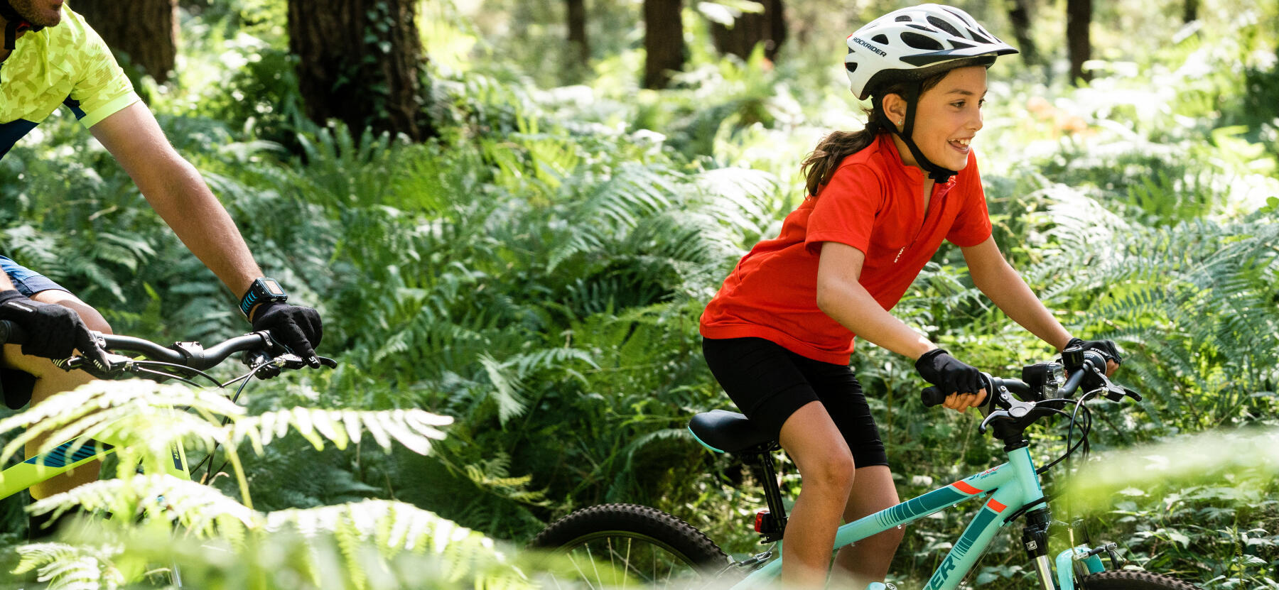 En flicka cyklar i skogsterräng