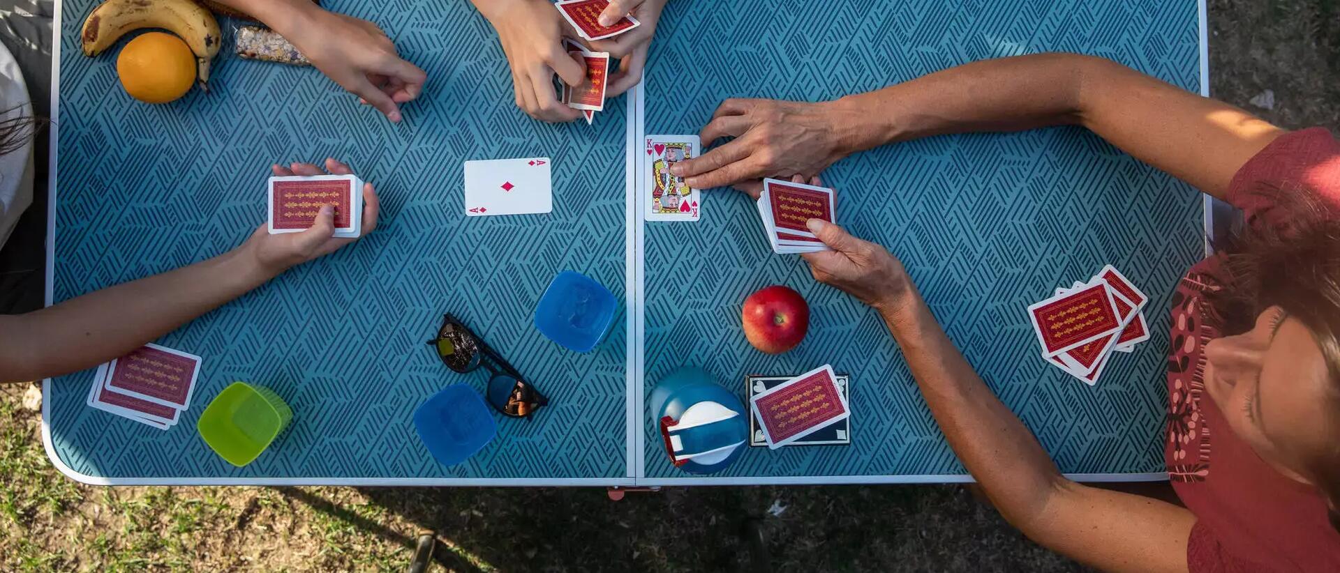 Menschen spielen Karten an einem Campingtisch 