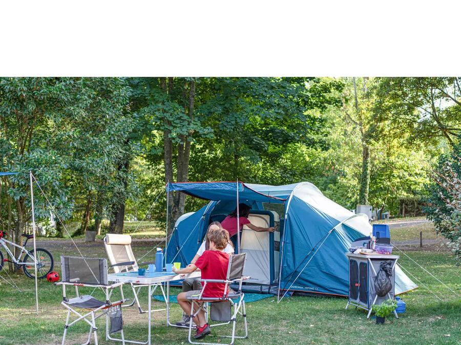 Campingzelt mit Stangenaufbau aufgebaut und Campingmöbel davor mit einer Person