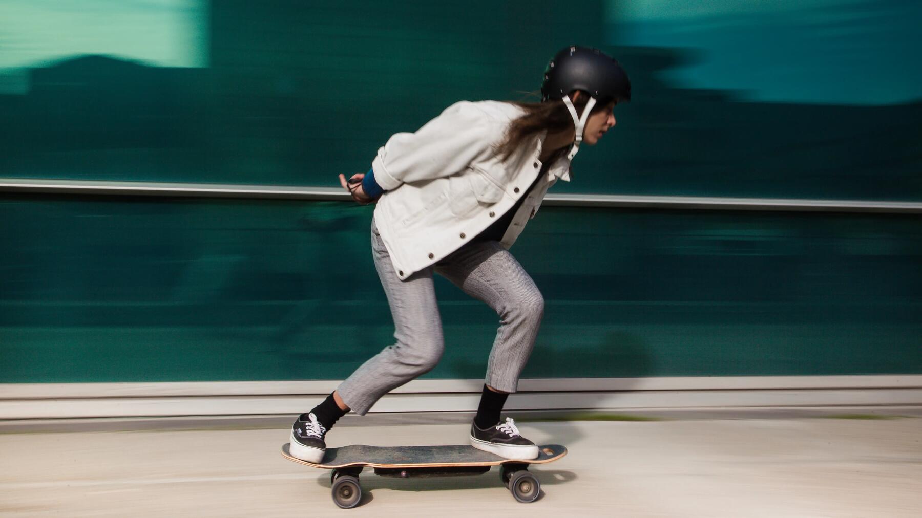 Konzentrierter Skateboarder beim Erlernen des Gleichgewichts auf dem rollenden Board