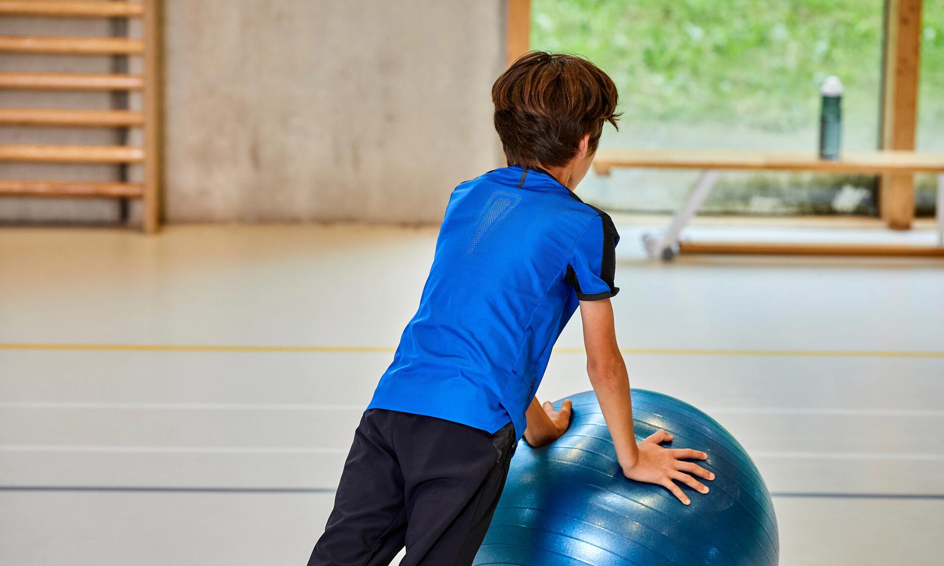 Junge macht Sportübungen mit einem Pezziball