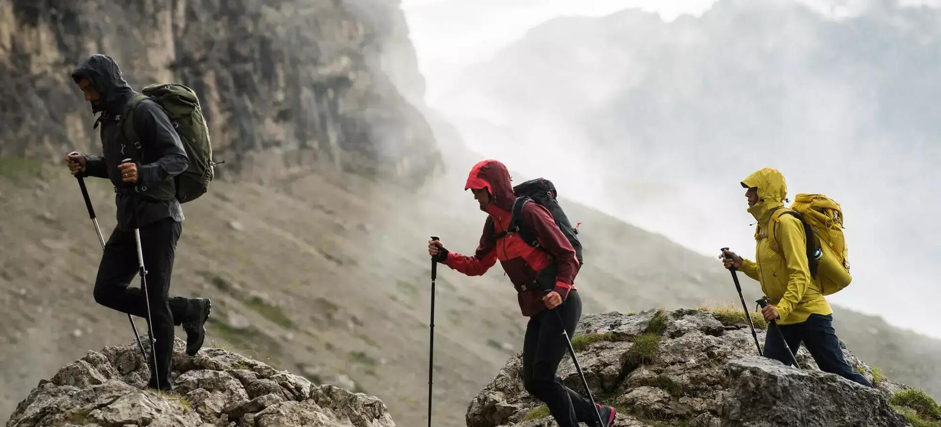 3 people hiking with walking poles in mountains