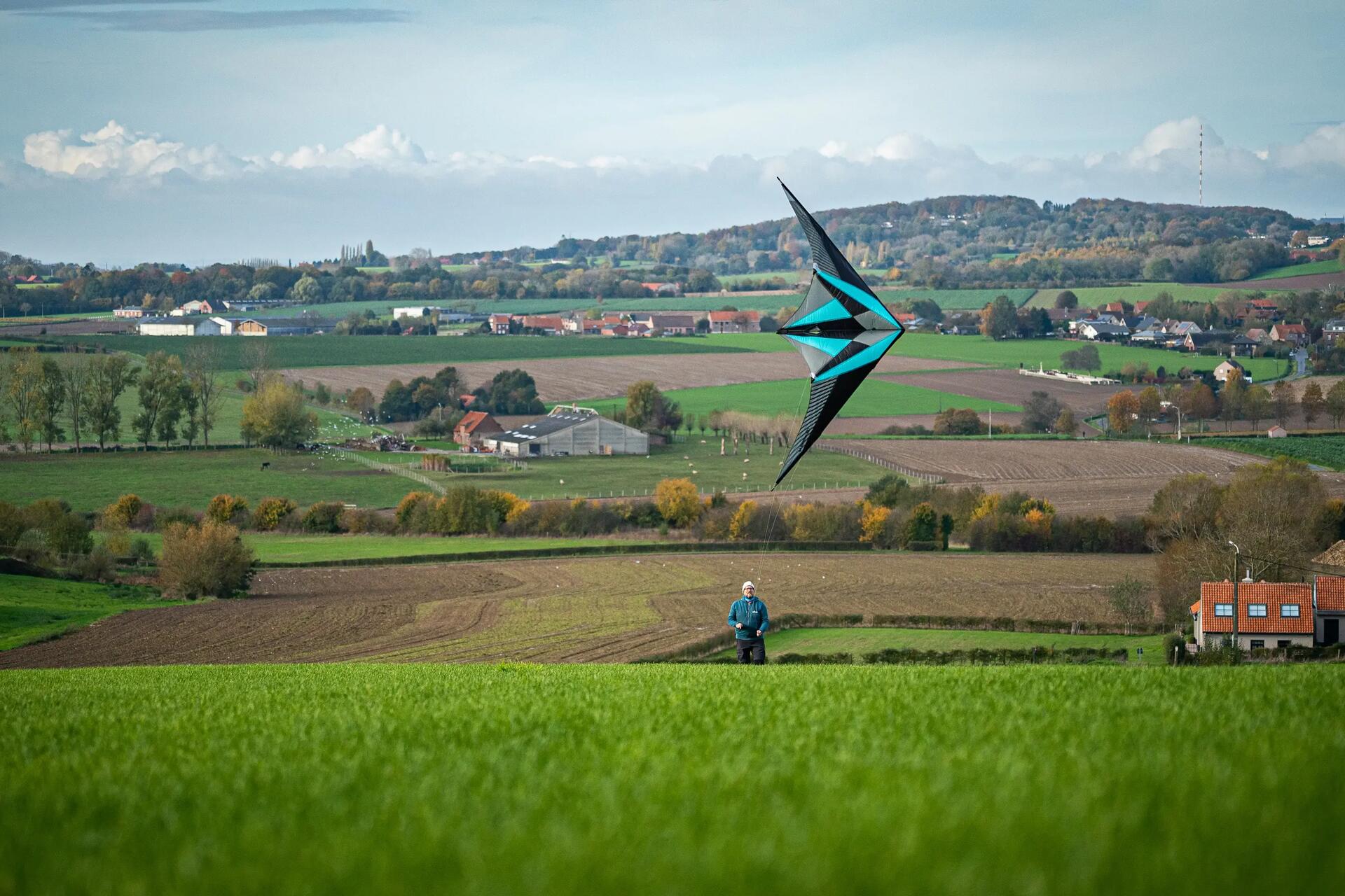Mann beim Lenkdrachensteigen in einer ländlichen Gegend auf offenem Feld