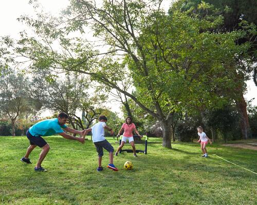 Parents et enfants qui jouent au foot dans son jardin