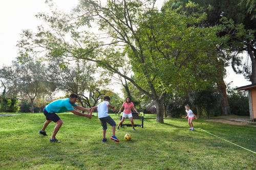 Parents et enfants qui jouent au foot dans son jardin