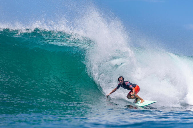Hombre surfeando una ola gigante sobre una tabla de surf