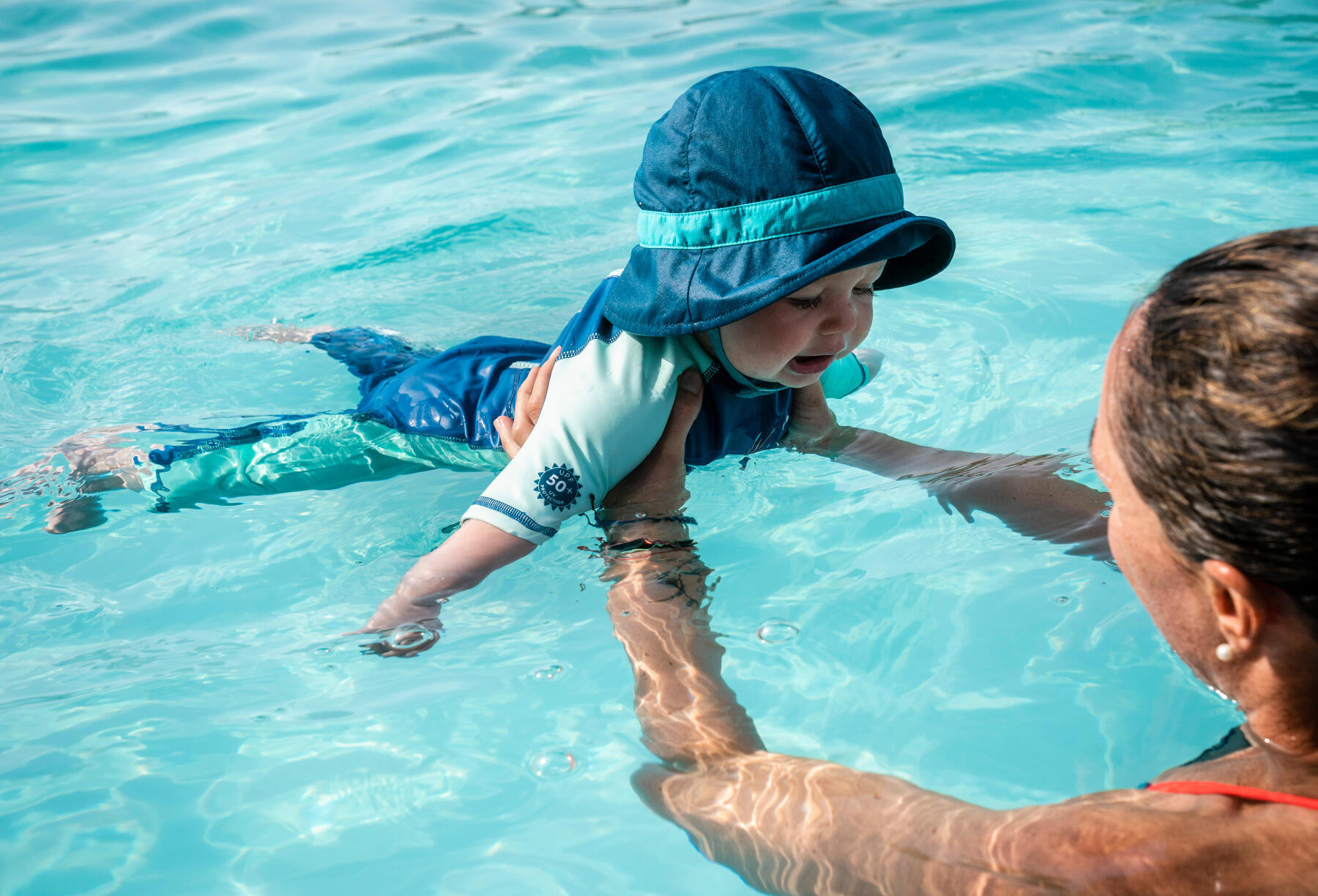 bébé qui apprend à utiliser ses bras dans la piscine avec maman