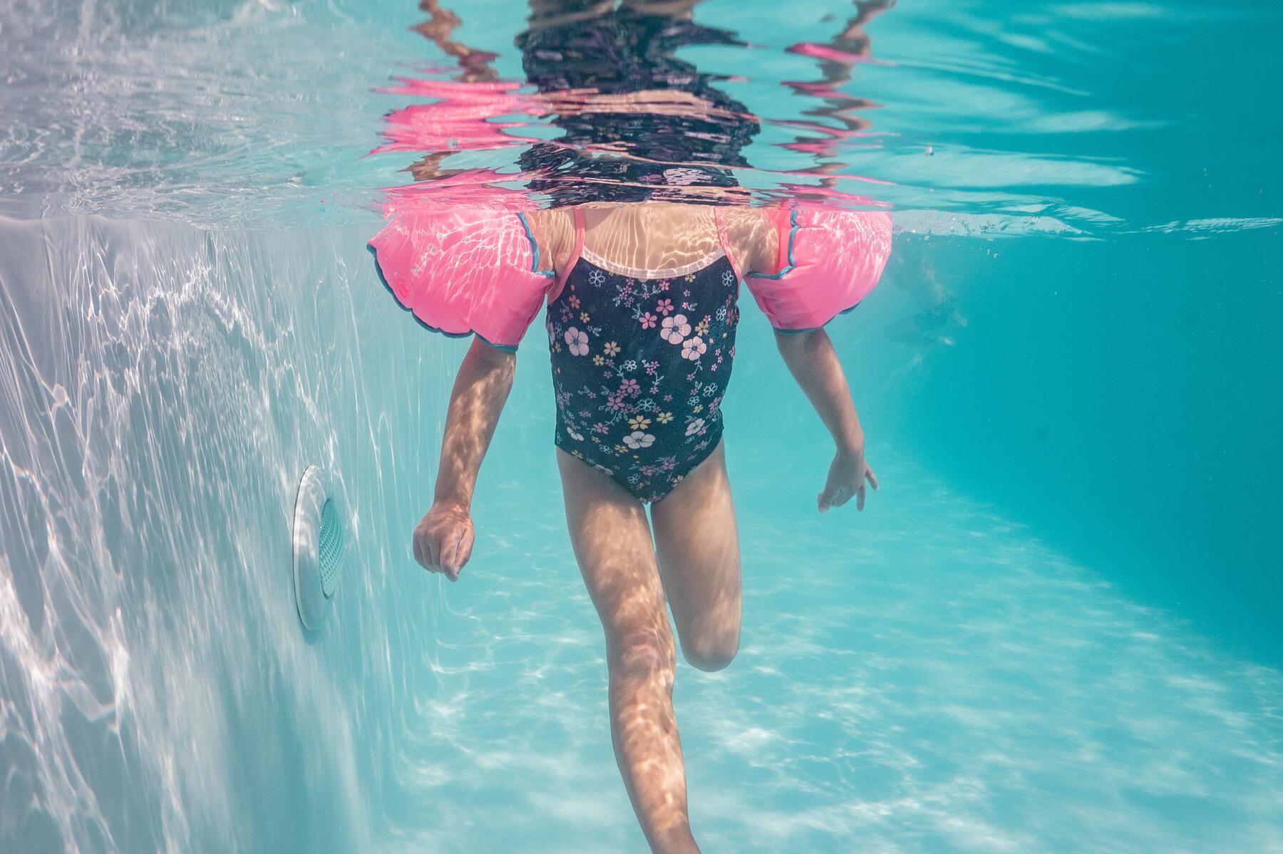 Ein Kind schwimmt mit Schwimmflügeln in einem Planschbecken