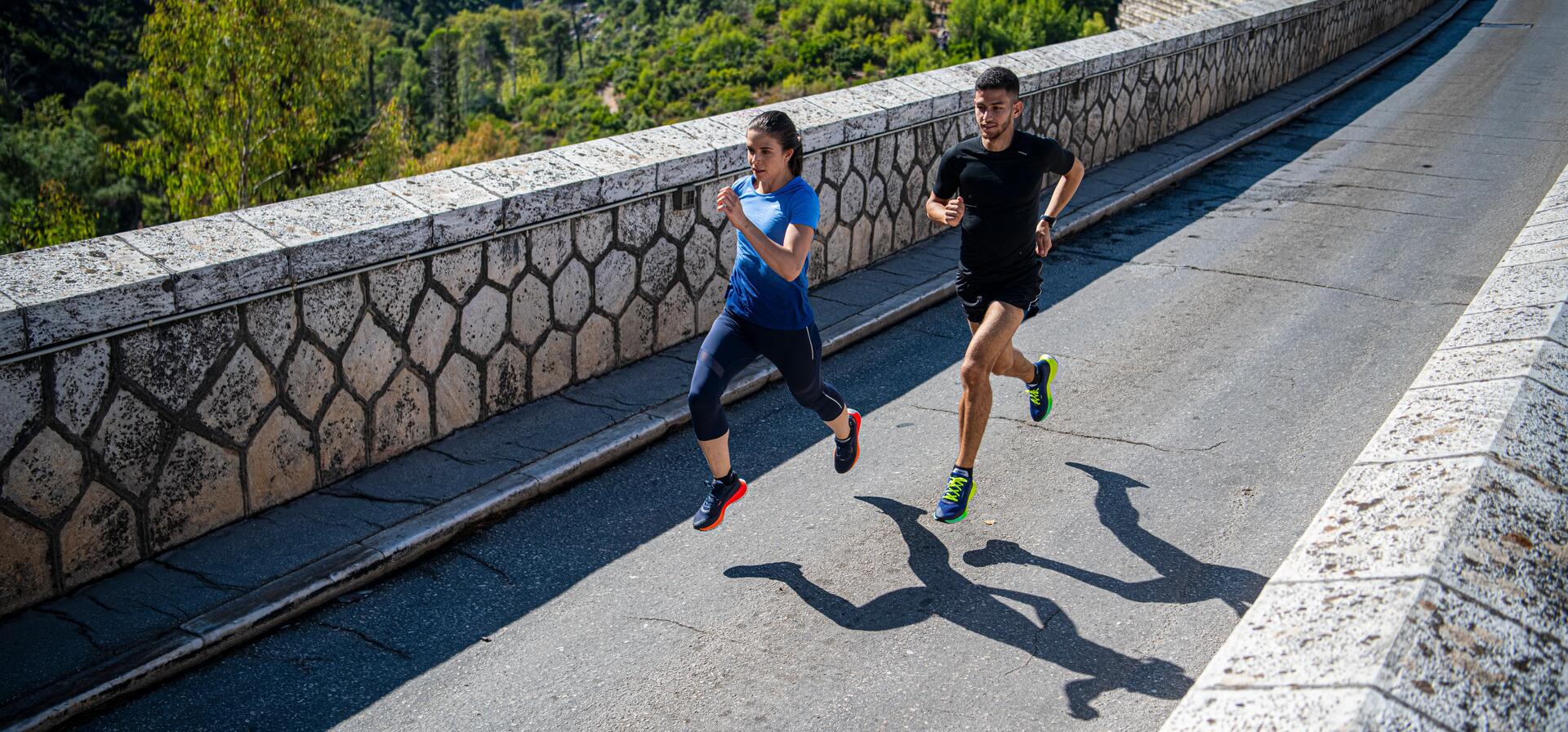 mężczyzna i kobieta biegnący w odzieży i butach do biegania po drodze asfaltowej
