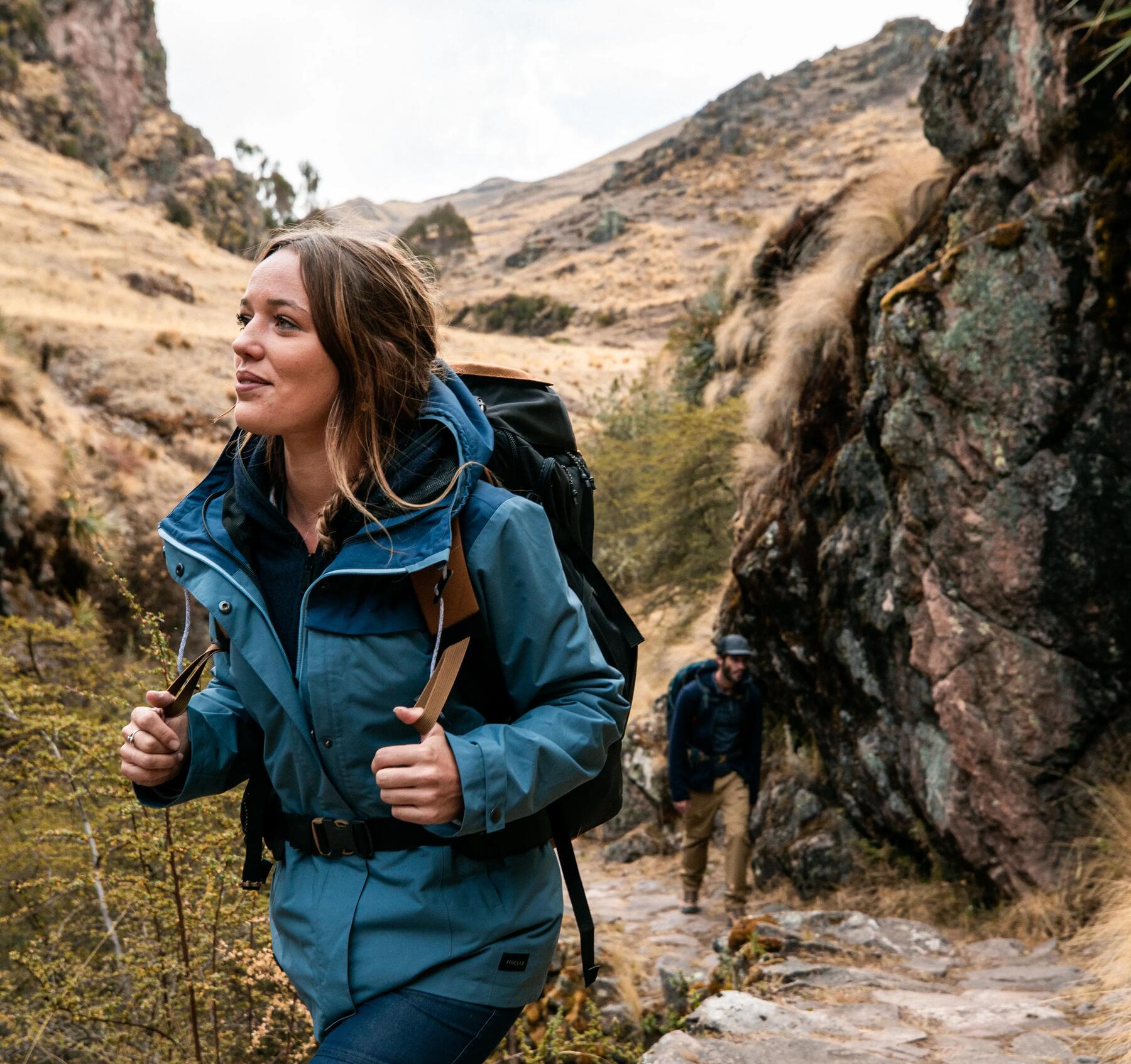 Frau wandert mit Rucksack in bergigem Gelände