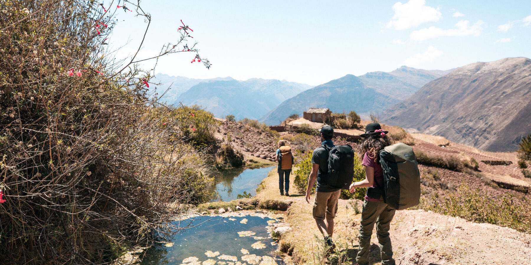 groupe d'amis qui marche dans un paysage montagneux, au bord d'un ruisseau