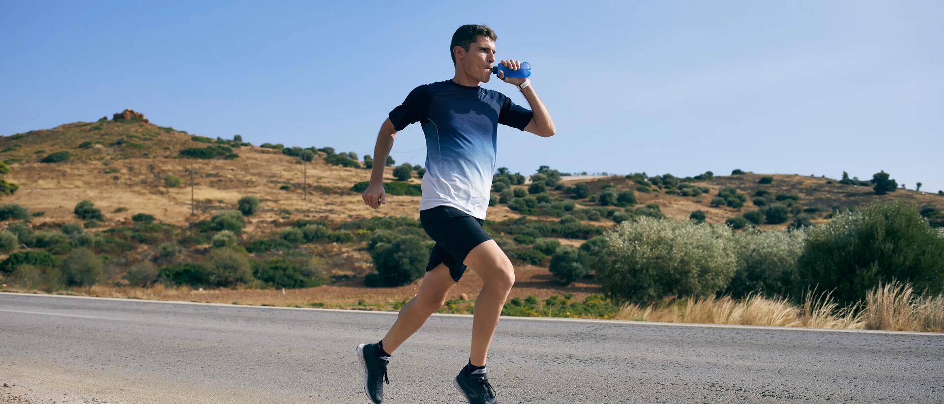 mężczyzna pijący wodę z bidonu biegnąc po drodze