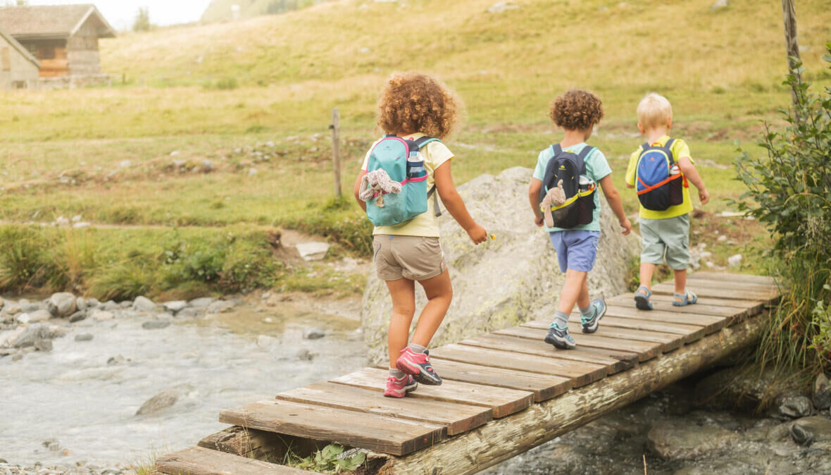 3 crianças a atravessar uma ponte de madeira na natureza decathlon