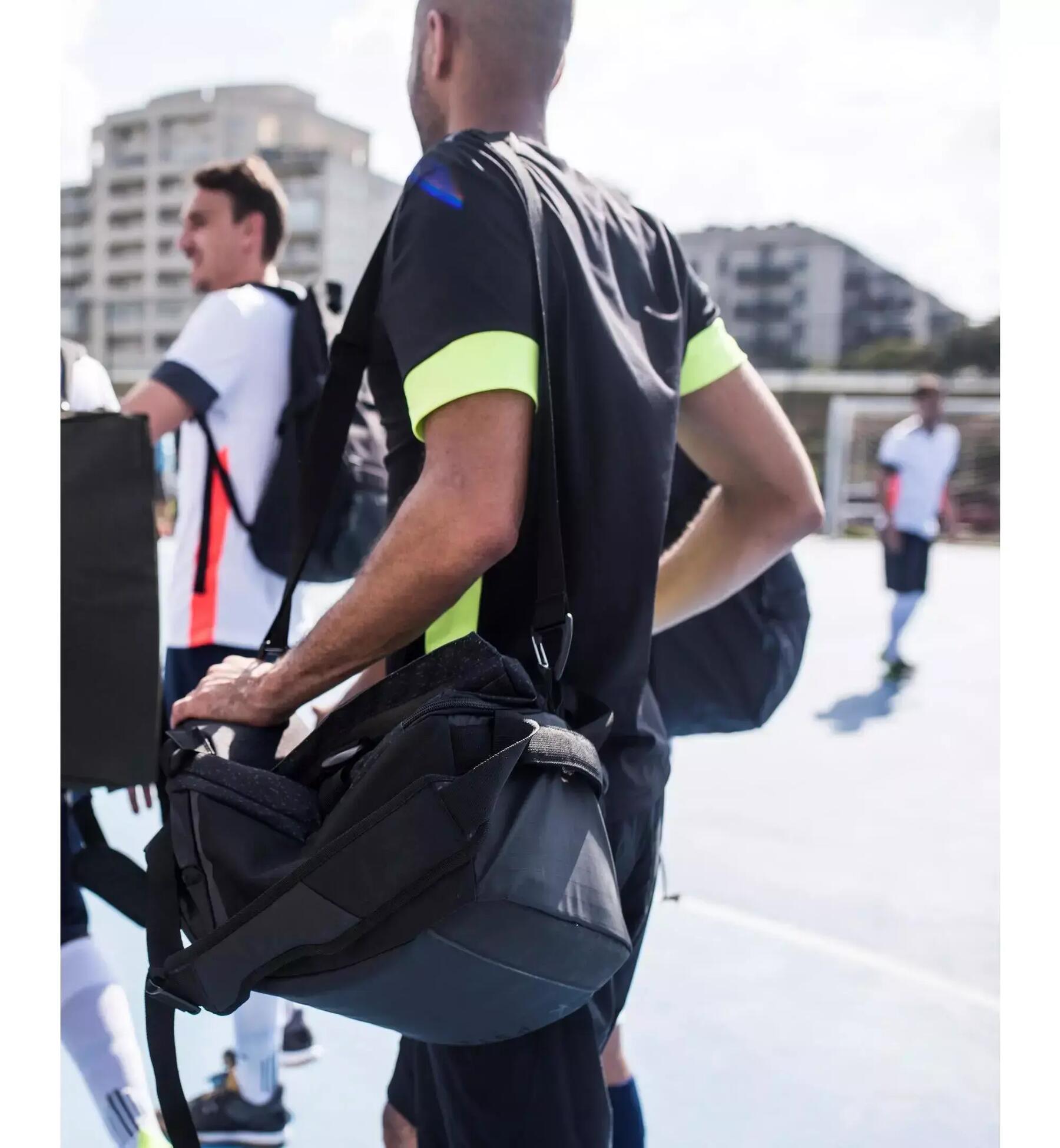 Mann trägt Sporttasche um die Schulter auf einem Sportplatz