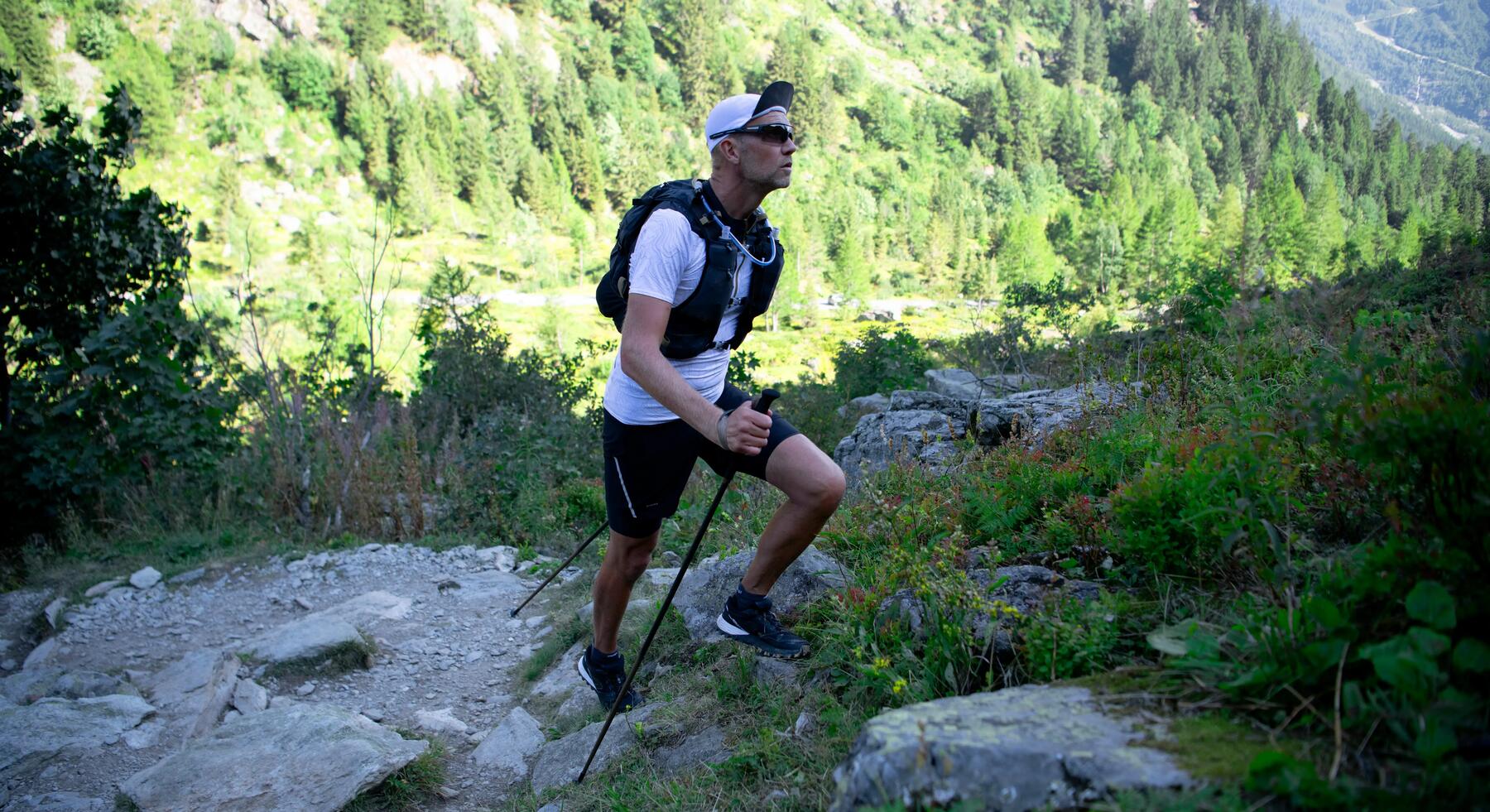 Mann wandert mit Wanderstöcken einen steinigen Weg entlang