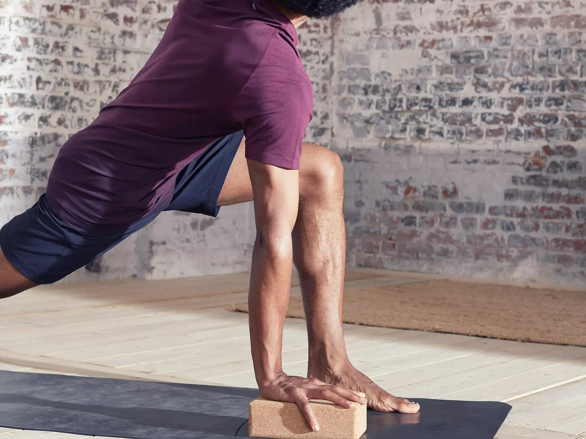 Homme s'appuyant sur un bloc de liège pour maintenir une pose de yoga