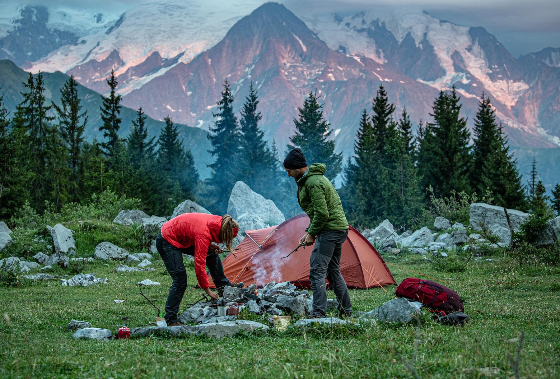 Man and woman setting camp fire outside