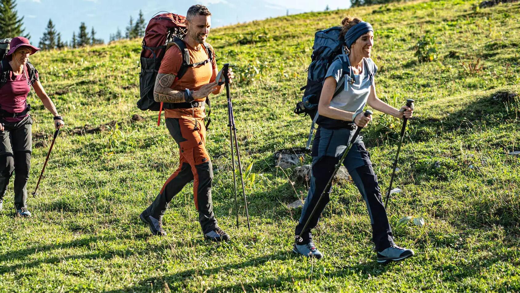 kobiety i mężczyzna idący w odzieży trekkingowej z kijami trekkingowymi w rękach 