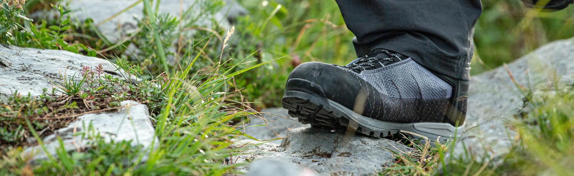 mężczyzna idący w butach trekkingowych po kamieniach