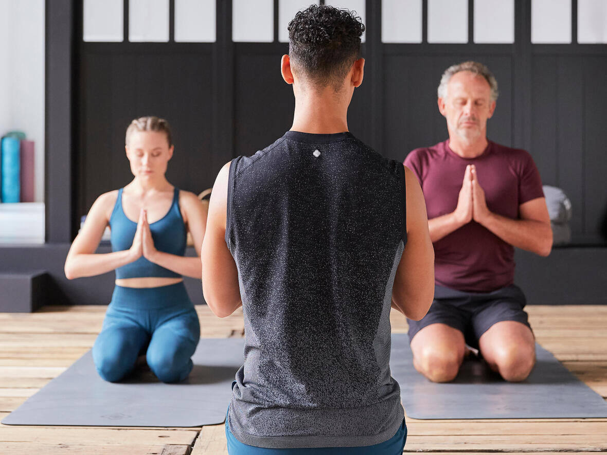 People in sitting poses meditate in a yoga studio.