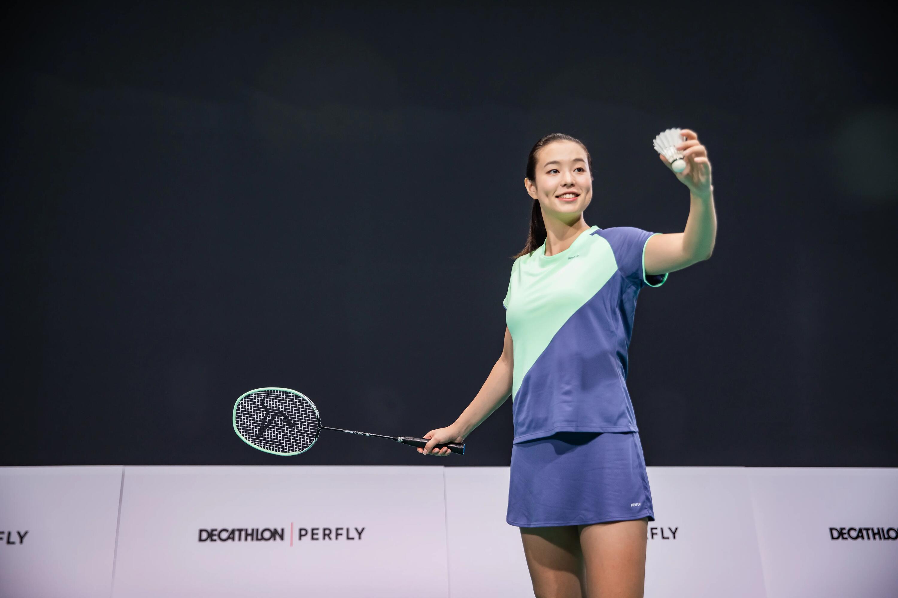 Kobieta w stroju badmintonowym trzymająca rakietkę i lotkę do gry w badmintona