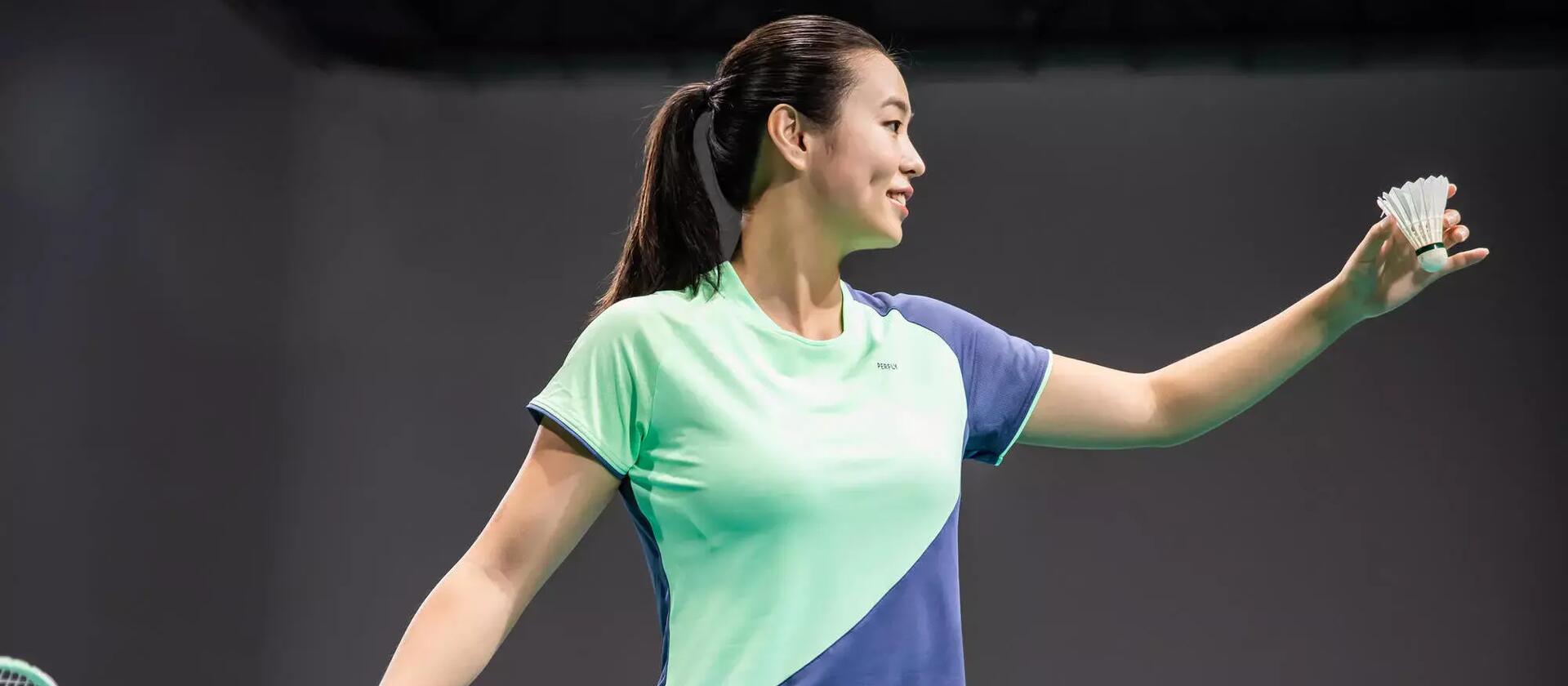kobieta w odzieży do badmintona trzymająca lotkę i rakietę badmintonową